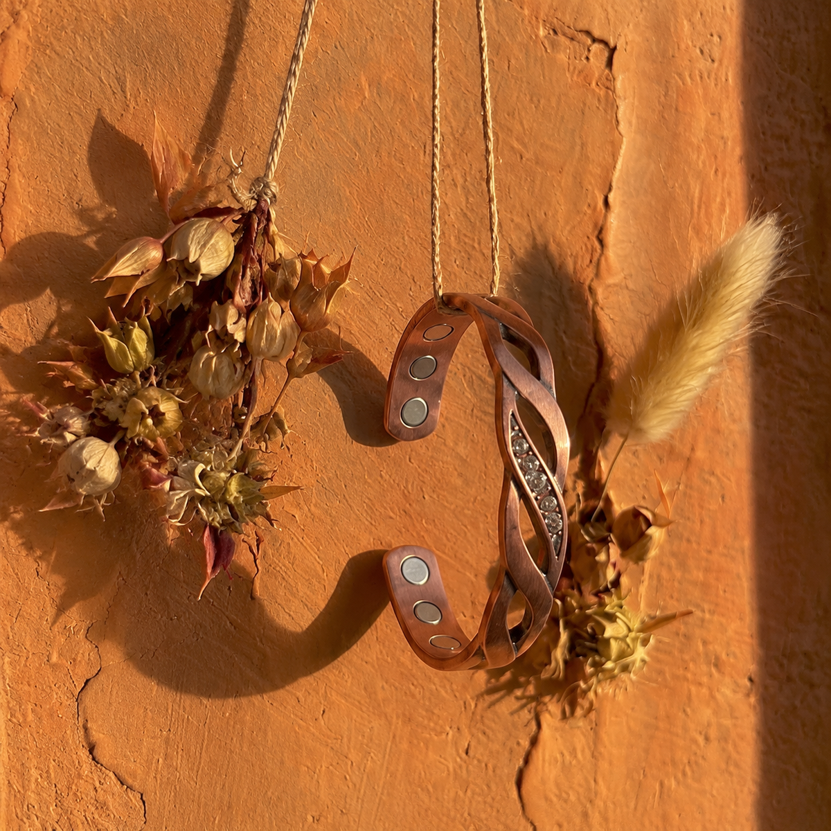 Cuivre Ysoline crystal twist copper cuff bracelet hanging on a terracotta wall