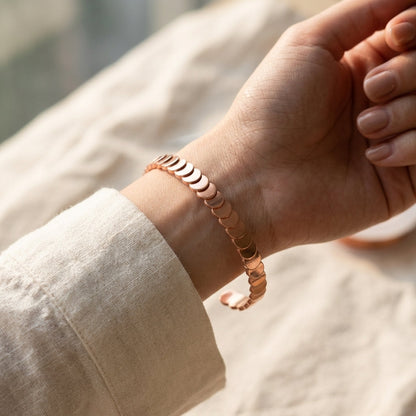 Woman wearing Cuivre Maëlle copper cuff bracelet on wrist with cream linen sleeve