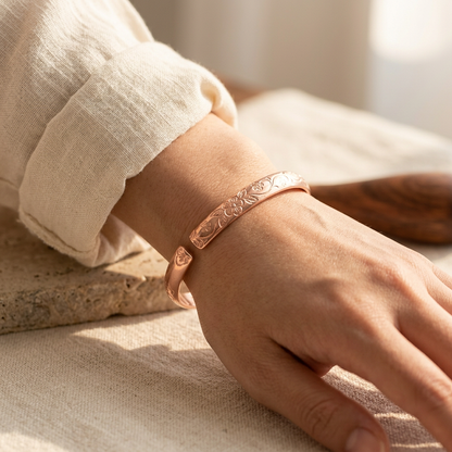 Woman wearing Cuivre Ninon copper cuff bracelet on wrist with cream linen sleeve