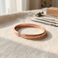 Cuivre Ninon plum blossom copper cuff bracelet on natural linen with warm lighting