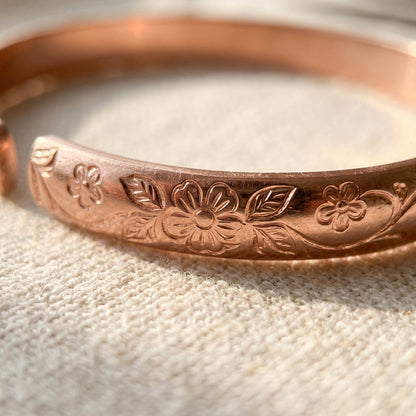 Close-up of plum-blossom engraving on Cuivre Ninon copper cuff bracelet